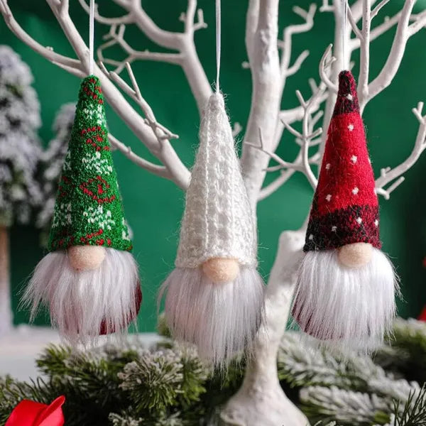 Three knitted gnome ornaments hanging on a branch with a green background
