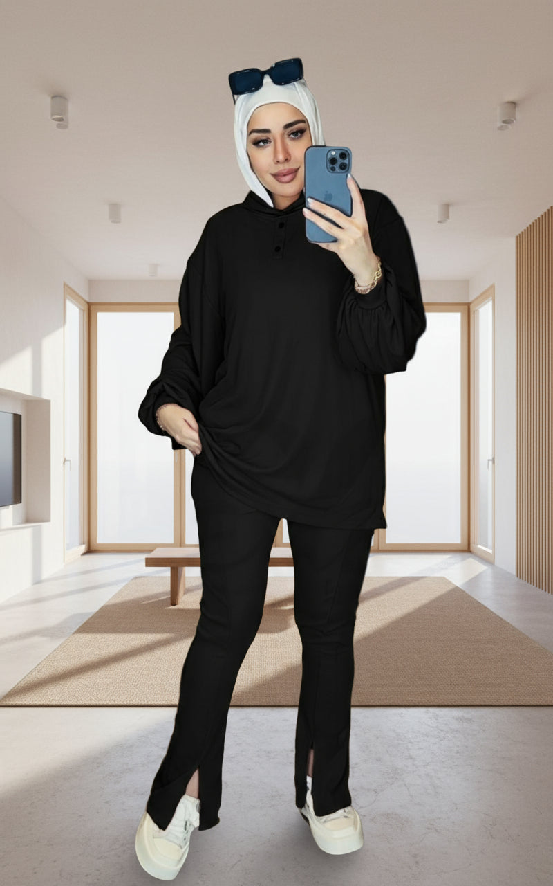 Person wearing a black outfit with a white headscarf, standing in front of a mirror with a visible brand logo.